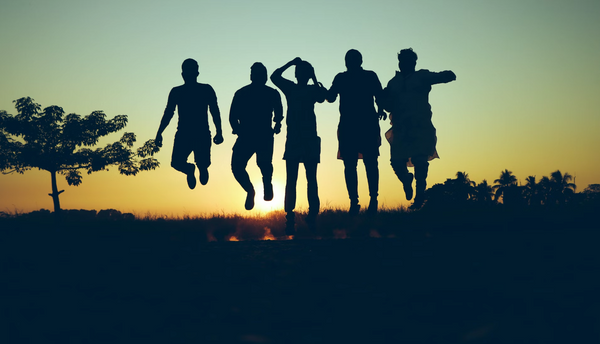 A group of friends jumping and enjoying an outdoor sunset, symbolizing the energy and vitality experienced with kratom use.